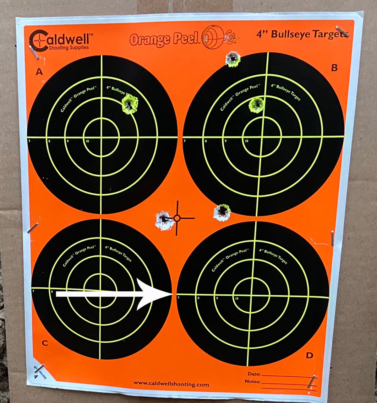 Two 150-yard groups. Top 3 aimed at center of paper, hot barrel. Arrow indicates aim point for bottom cold-barrel group. (Photo © Russ Chastain)